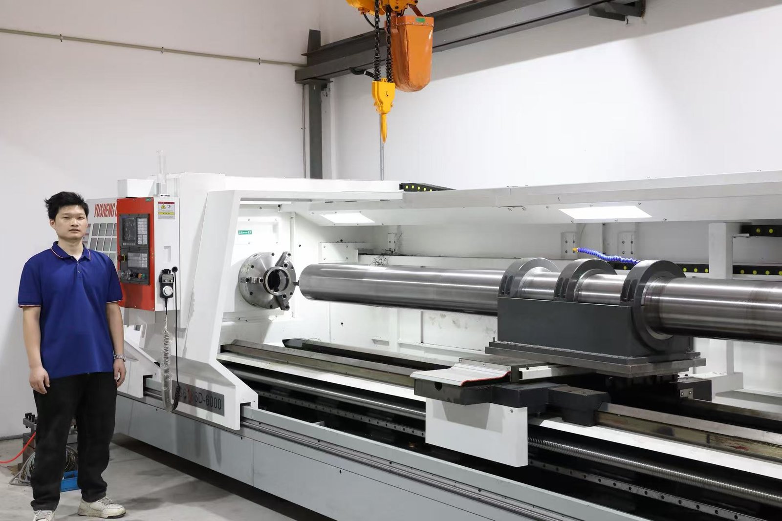 Operator beside a large CNC lathe and workpiece in the production workshop
