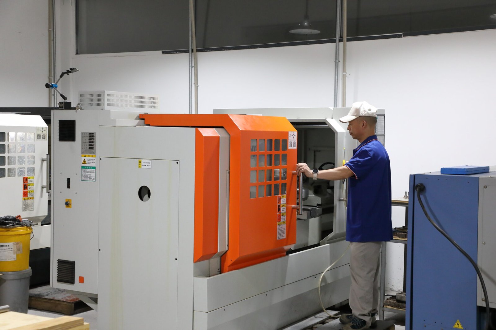Operator opening a CNC machine enclosure in the production workshop